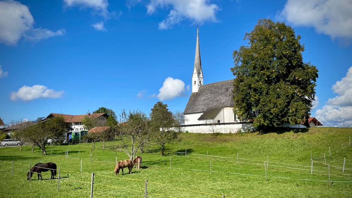 Blick auf die Filialkirche St. Margaretha in Einharting mit Pferdekoppel im Vordergrund