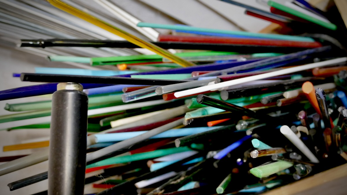 Bunte Glasstäbe als Rohmaterial für handgefertigte Perlen in einer Werkstatt
