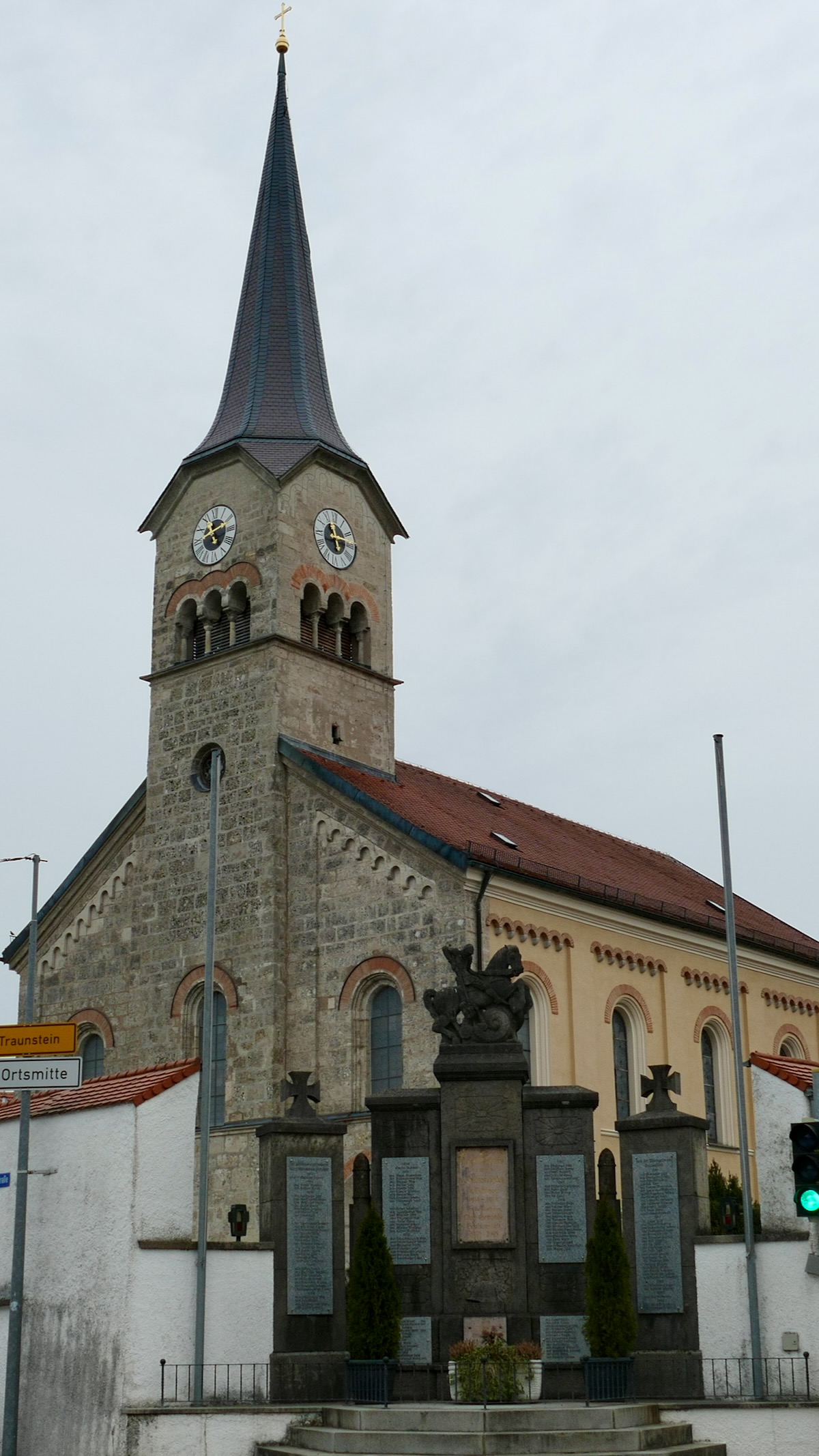 Pfarrkirche St. Maximilian in Grabenstätt mit neuromanischem Turm und Spitzhelm, davor das Kriegerdenkmal