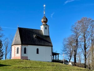 Filialkirche St. Johann in Siegsdorf mit barocker Zwiebelhaube auf dem Turm, spätgotischer Saalbau mit erhaltenen romanischen Fundamenten.
