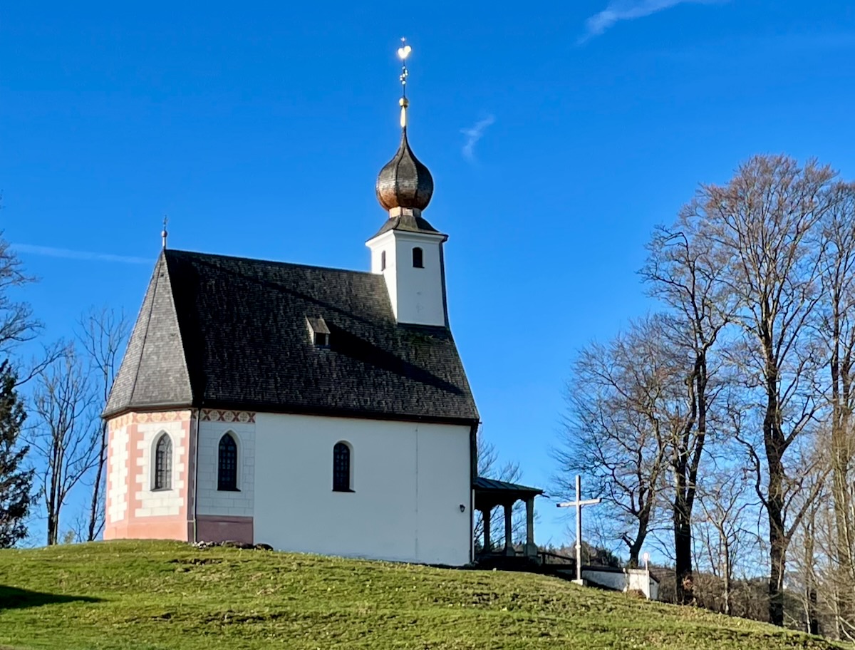Filialkirche St. Johann in Siegsdorf mit barocker Zwiebelhaube auf dem Turm, spätgotischer Saalbau mit erhaltenen romanischen Fundamenten.