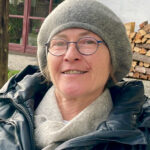 Porträt der Künstlerin Angelika Gimpl mit grauer Mütze und Brille